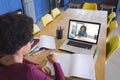 African american girl writing in notebook while taking notes from friend though video call on laptop Royalty Free Stock Photo