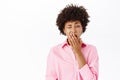 African american girl yawns, office worker looks sleepy or bored, covers open mouth, stands over white background
