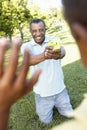 African American Grandfather And Grandson Playing With Water Pistols In Park