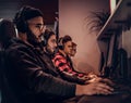 A young African American guy, enjoying spending time with his friends, playing in a multiplayer video game on a PC in a Royalty Free Stock Photo