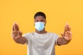 African american guy in face mask gesturing STOP to camera, expressing negativity towards coronavirus pandemic