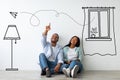 African american guy and his girlfriend imagining their new furnished home against white wall with interior drawings Royalty Free Stock Photo