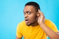 African American Guy Listening Holding Hand Near Ear, Blue Background