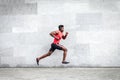 African American guy runner runs fast forward against the background of the city wall, sports man train on the street