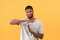 African american guy showing TIME OUT or STOP gesture taking break or pause, yellow studio background,