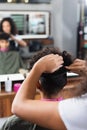 African american hairstylist combing hair of