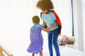 African American happy and confident young kids playing and dressing up as superhero together in bedroom