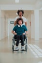 African-American hospital technician compassionately navigating the hospital hallways, pushing his wheelchair-bound