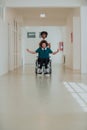 African-American hospital technician compassionately navigating the hospital hallways, pushing his wheelchair-bound