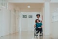 African-American hospital technician compassionately navigating the hospital hallways, pushing his wheelchair-bound