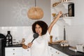 African american housewife in apron singing with spatulas for cooking microphone on the kitchen. Joyful African young Royalty Free Stock Photo