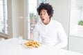 African American hungry man eating hamburger for lunch afraid and shocked with surprise expression, fear and excited face Royalty Free Stock Photo
