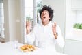 African American hungry man eating hamburger for lunch celebrating mad and crazy for success with arms raised and closed eyes Royalty Free Stock Photo