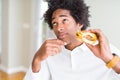 African American hungry man eating hamburger for lunch serious face thinking about question, very confused idea