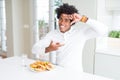 African American hungry man eating hamburger for lunch smiling making frame with hands and fingers with happy face