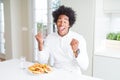 African American hungry man eating hamburger for lunch very happy and excited doing winner gesture with arms raised, smiling and Royalty Free Stock Photo