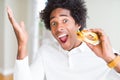 African American hungry man eating hamburger for lunch very happy and excited, winner expression celebrating victory screaming Royalty Free Stock Photo