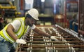 African American industrial worker is checking the setup value of metal sheet roll forming machine inside roof factory for safety Royalty Free Stock Photo