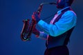 African-American jazz musician playing saxophone his major melodies against blue background in mixed pink-purple Royalty Free Stock Photo