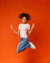 African-american joyful lady jumping and gesturing peace