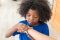 African American kid checking time on digital wristwatch