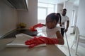 Little girl diligently cleaning the kitchen with father