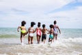 African American, Kids group in swimwear enjoying running to play the waves on beach. Ethnically diverse concept. Having fun after