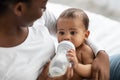 African American lady feeding her child from baby bottle Royalty Free Stock Photo