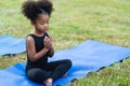 African American little girl sitting on the roll mat practicing meditate yoga in the park outdoor Royalty Free Stock Photo