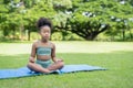 African American little girl sitting with their eyes closed on roll mat practicing meditate yoga in the park. Kids afro girl with Royalty Free Stock Photo