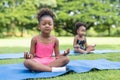 African American little girls sitting with their eyes closed on roll mat practicing meditate yoga in the park. Kids afro girls Royalty Free Stock Photo