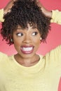 African American looking sideways with hands in hair over colored background Royalty Free Stock Photo