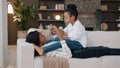 African American loving mother mommy lying on sofa relaxing at home living room with little daughter child talking Royalty Free Stock Photo