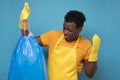 African american male in apron and gloves holding a stinky garbage bag Royalty Free Stock Photo