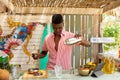 African american male bartender holdind shaker and preparing cocktails in beach bar, unaltered Royalty Free Stock Photo