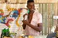 African american male bartender holding shaker and preparing cocktails in beach bar, unaltered Royalty Free Stock Photo