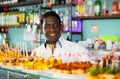 African american male bartender standing behind bar counter in pub and offering plate of pinchos