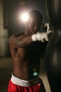 African American male boxer hitting punch bag in red shorts at the gym Royalty Free Stock Photo