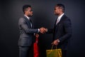 African american male business partners holding shopping bags on a black background in the studio.black Friday sale