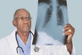 African American male doctor analyzing x-ray report over light blue background