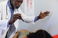 African american male doctor examinating sight of biracial female patient at doctor's office