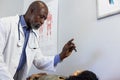 African american male doctor examinating sight of biracial female patient at doctor\'s office