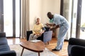 African american male doctor examining blood pressure of caucasian senior woman with gauge at home