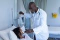 African american male doctor putting oxygen mask ventilator on sick mixed race girl in hospital bed Royalty Free Stock Photo