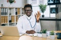 African American male doctor sitting at office and holding stethoscope