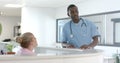 African american male doctor talking to medical recepcionist at front desk at hospital, slow motion