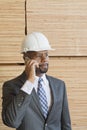 African American male engineer on phone call with stacked wooden planks in background