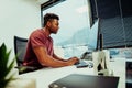 African American male entrepreneur researching logo designs for company using desktop laptop sitting in fancy office Royalty Free Stock Photo