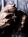 African American male hands praying holding a beads rosary with Jesus Christ in the cross or Crucifix on black background Royalty Free Stock Photo