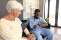 African american male health worker checking blood pressure of caucasian senior woman at home Royalty Free Stock Photo